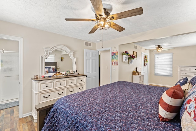 bedroom featuring a textured ceiling, ceiling fan, wood finished floors, and visible vents