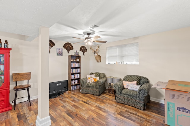 living area with a textured ceiling, wood finished floors, a ceiling fan, and baseboards