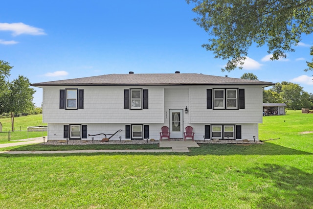 bi-level home featuring a shingled roof, a front lawn, and a patio