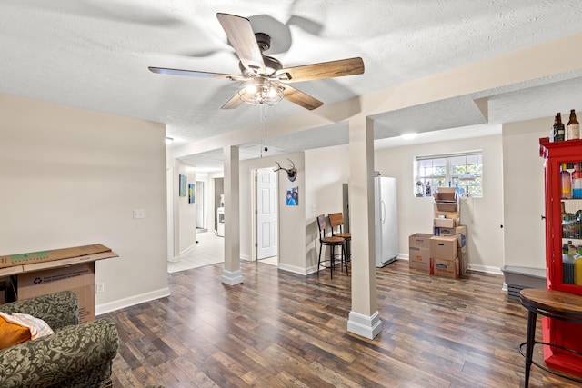 living room with a textured ceiling, baseboards, and wood finished floors