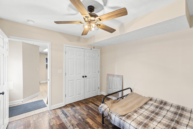 bedroom featuring a ceiling fan, a closet, baseboards, and wood finished floors