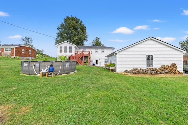 view of yard with an outdoor pool, a wooden deck, and stairs