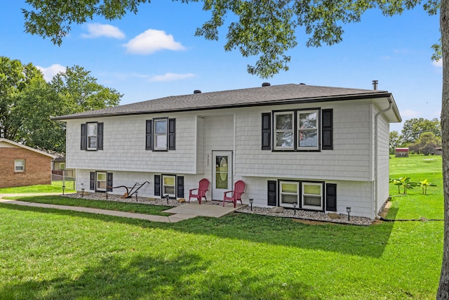 split foyer home with a front lawn, roof with shingles, and a patio area