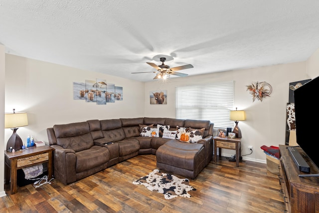 living room featuring a ceiling fan, a textured ceiling, baseboards, and wood finished floors