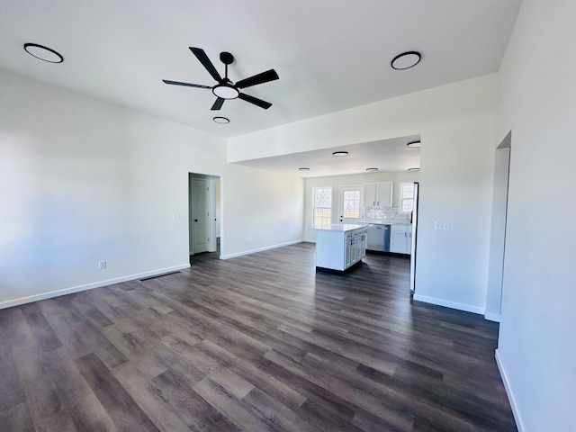 unfurnished living room with dark wood-type flooring, ceiling fan, and baseboards