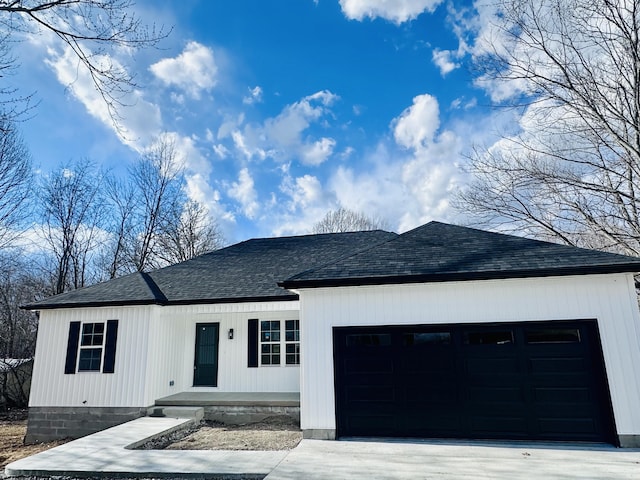 view of front facade with driveway, roof with shingles, and an attached garage