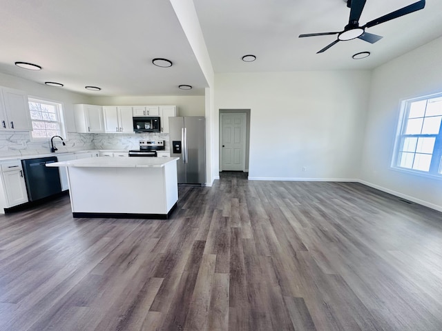 kitchen featuring tasteful backsplash, a kitchen island, appliances with stainless steel finishes, white cabinetry, and a sink