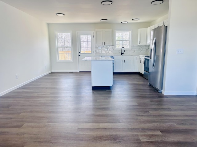 kitchen featuring a center island, range with electric stovetop, tasteful backsplash, white cabinets, and stainless steel fridge