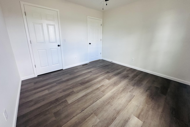 unfurnished bedroom with visible vents, baseboards, and dark wood-type flooring