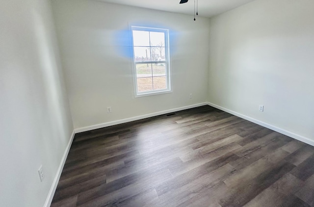 empty room featuring ceiling fan, dark wood-type flooring, visible vents, and baseboards