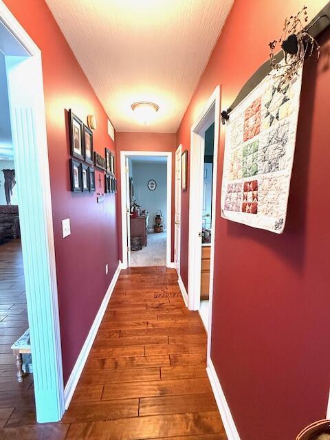 corridor with hardwood / wood-style flooring, baseboards, and a textured ceiling