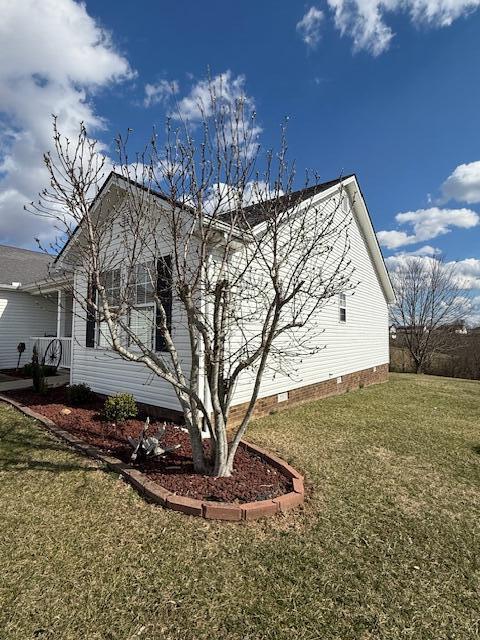 view of side of home with crawl space and a lawn