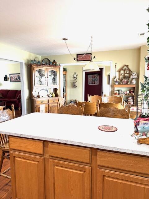 kitchen with brown cabinetry, light countertops, visible vents, and a breakfast bar area