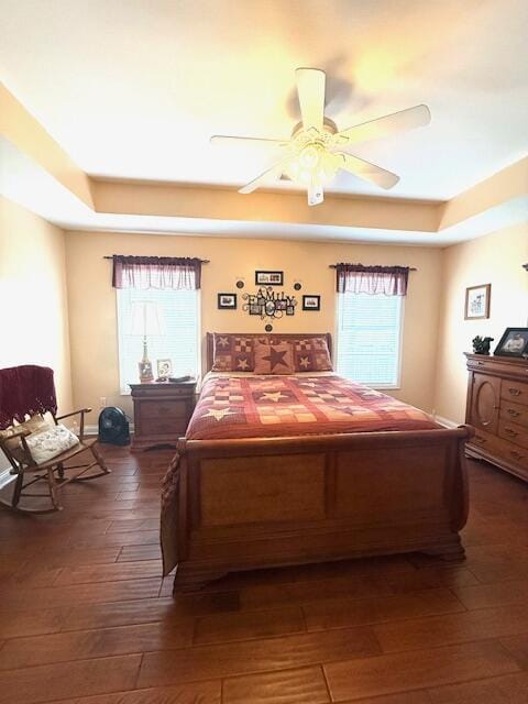 bedroom featuring ceiling fan, a raised ceiling, and dark wood-style flooring