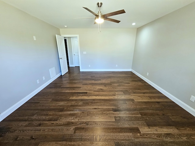 empty room featuring a ceiling fan, dark wood finished floors, visible vents, and baseboards