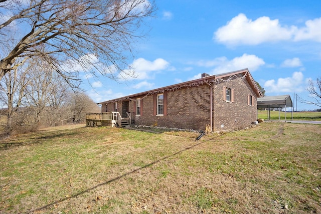 view of side of home with a detached carport, brick siding, a yard, and a deck