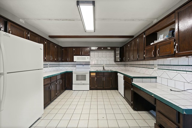 kitchen featuring tile countertops, decorative backsplash, dark brown cabinetry, a sink, and white appliances