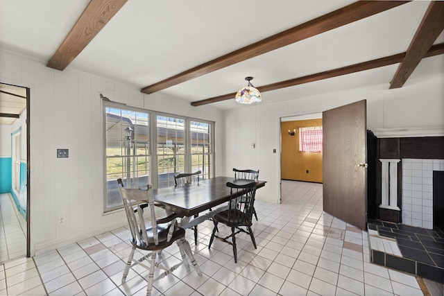 dining space with beam ceiling, baseboards, a tiled fireplace, and light tile patterned floors