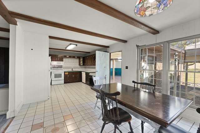 dining area with light tile patterned floors and beam ceiling