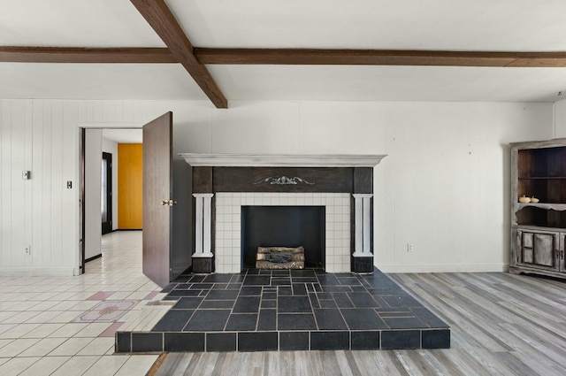 unfurnished living room with a fireplace, wood finished floors, beam ceiling, and baseboards