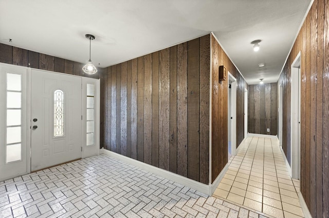 entrance foyer with baseboards, light tile patterned flooring, and wooden walls