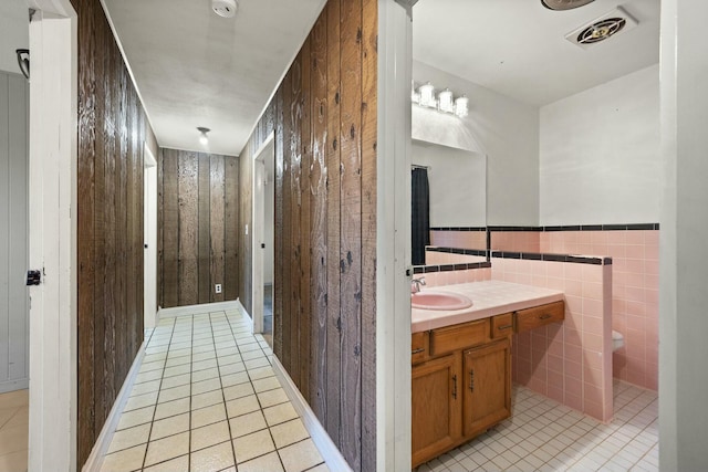 bathroom featuring visible vents, toilet, tile patterned flooring, vanity, and wood walls