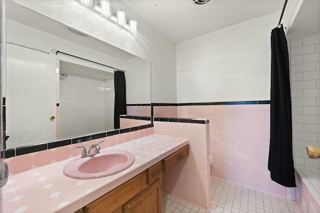 bathroom with wainscoting, toilet, tile patterned flooring, vanity, and tile walls