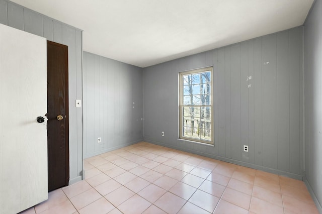 spare room featuring light tile patterned flooring and baseboards