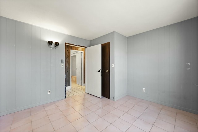 unfurnished room with light tile patterned floors and baseboards