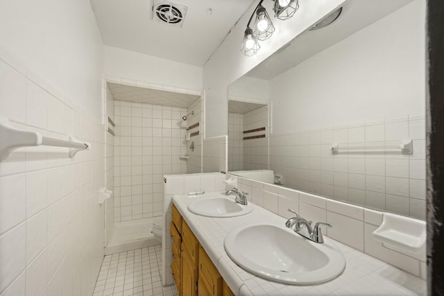 bathroom with visible vents, a sink, and tiled shower