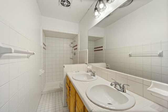 full bathroom with a tile shower, a sink, and visible vents