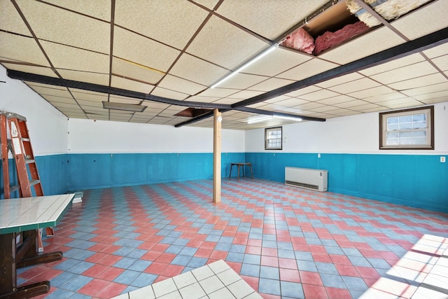 basement with tile patterned floors, a drop ceiling, and wainscoting