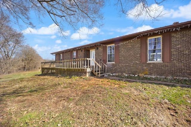 single story home featuring a front yard, a deck, and brick siding