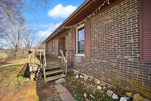 view of side of property featuring brick siding and a wooden deck