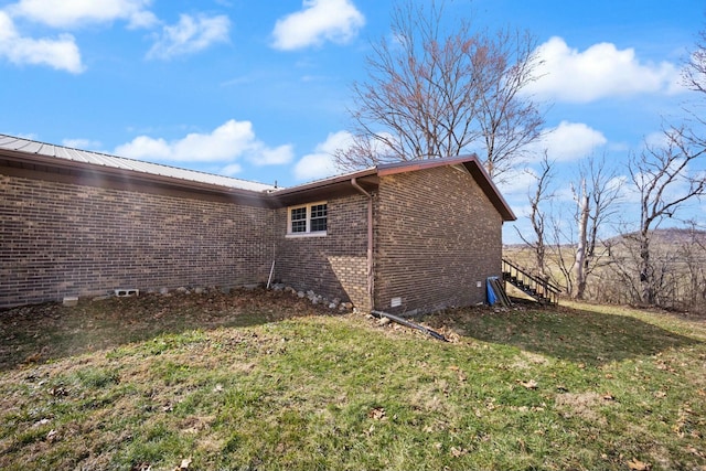 view of side of home featuring a yard, stairway, metal roof, and brick siding