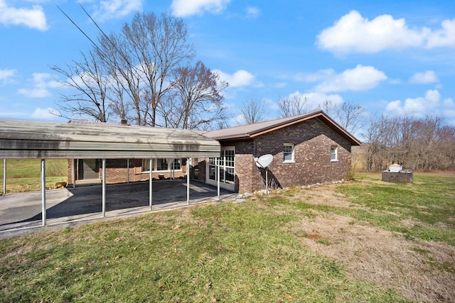 rear view of property with a yard, a carport, and brick siding