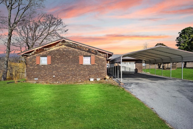 view of front facade with brick siding, driveway, crawl space, a lawn, and a detached carport