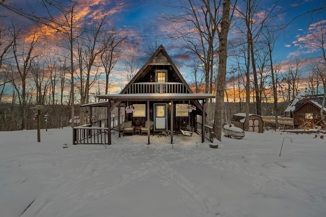 snow covered house featuring an outdoor structure and a storage unit