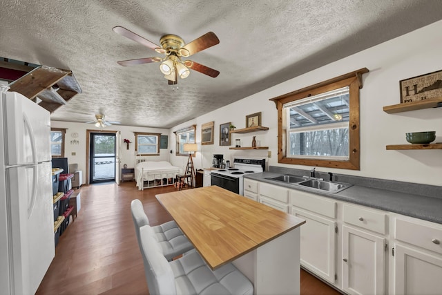 kitchen with open shelves, electric range oven, freestanding refrigerator, white cabinets, and a sink