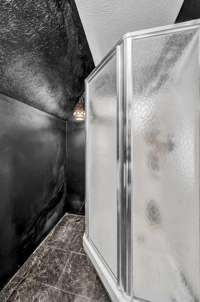 full bathroom with marble finish floor, vaulted ceiling, a textured ceiling, and a stall shower