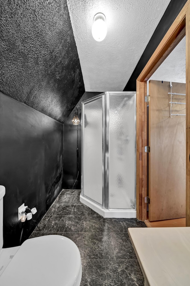 full bath with lofted ceiling, a shower stall, a textured ceiling, and toilet