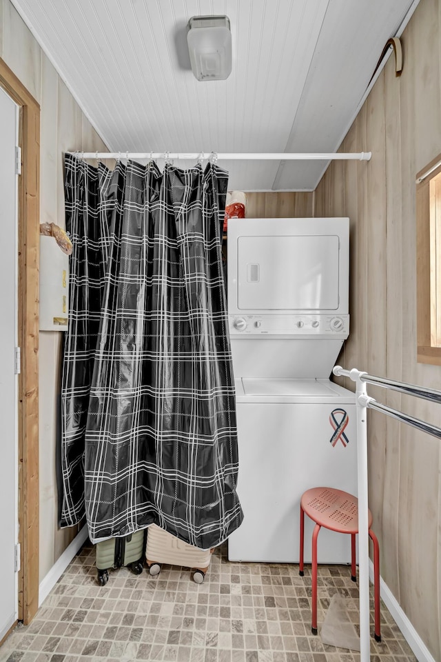 interior space featuring stacked washer / dryer, laundry area, wooden ceiling, and wood walls