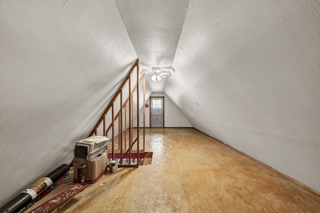 additional living space with lofted ceiling, a textured ceiling, and a textured wall