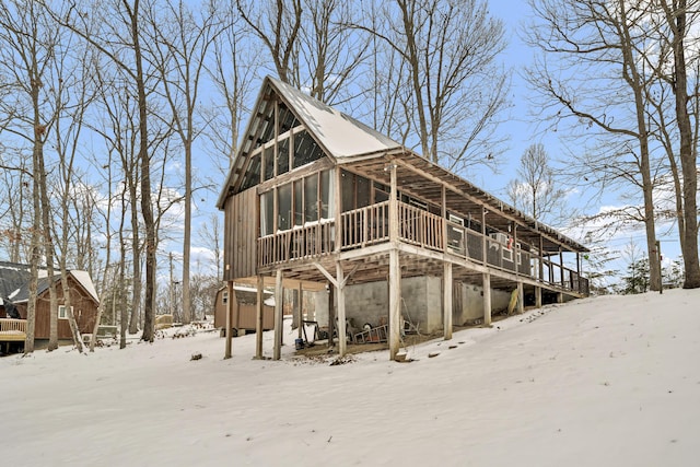 snow covered property with a sunroom and a wooden deck