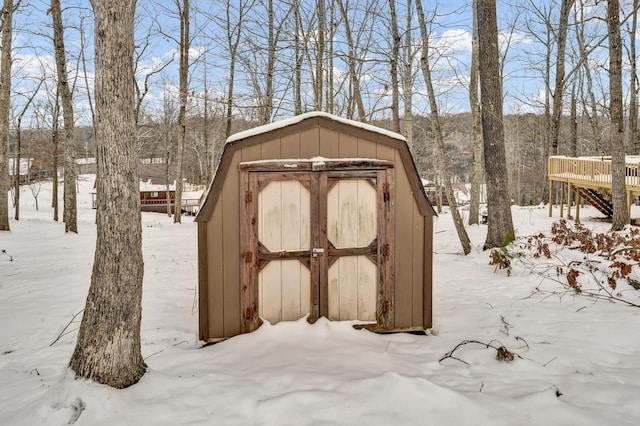 snow covered structure with an outdoor structure and a storage shed