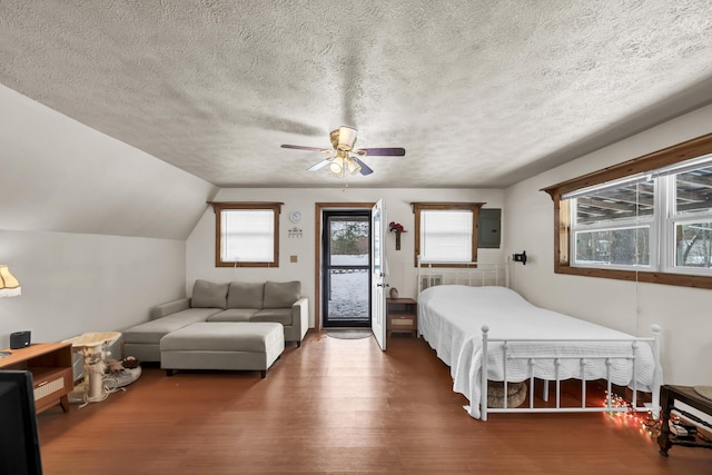 bedroom featuring electric panel, lofted ceiling, ceiling fan, wood finished floors, and access to exterior