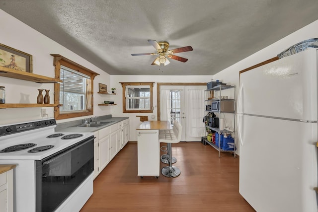 kitchen with electric range, a sink, white cabinetry, freestanding refrigerator, and open shelves