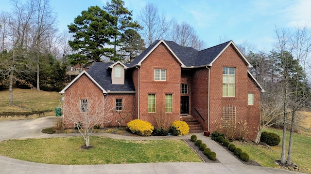 traditional home featuring concrete driveway, brick siding, and a front lawn