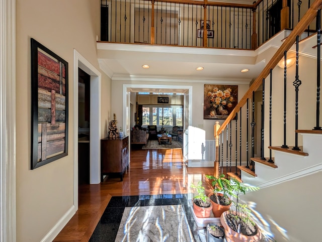 foyer with a towering ceiling, ornamental molding, wood finished floors, stairs, and recessed lighting