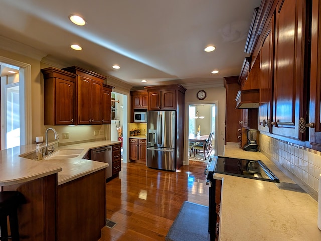 kitchen with a peninsula, stainless steel appliances, a sink, and light countertops